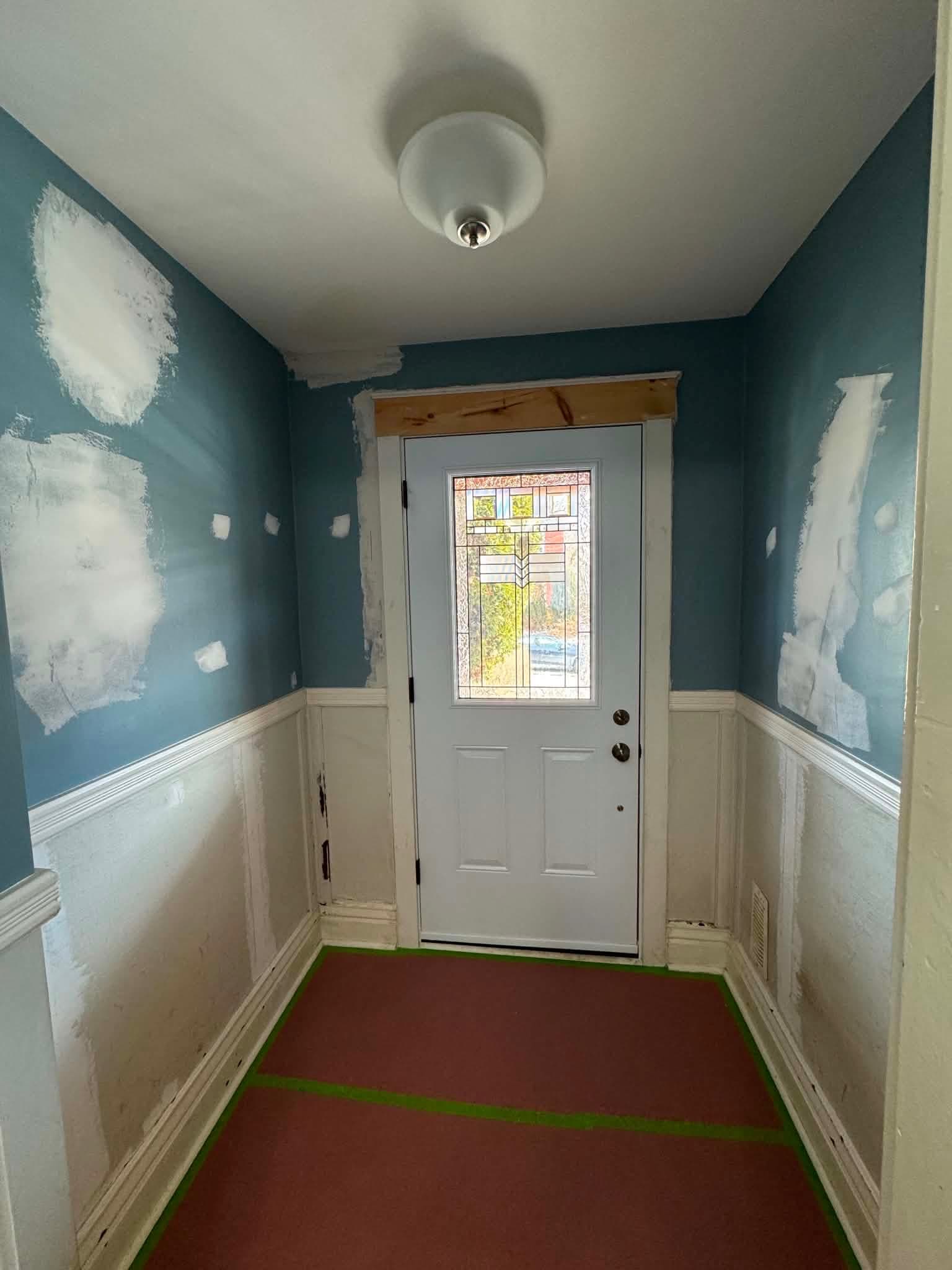 An older Toronto home entryway before renovation, with damaged plaster walls and worn trim