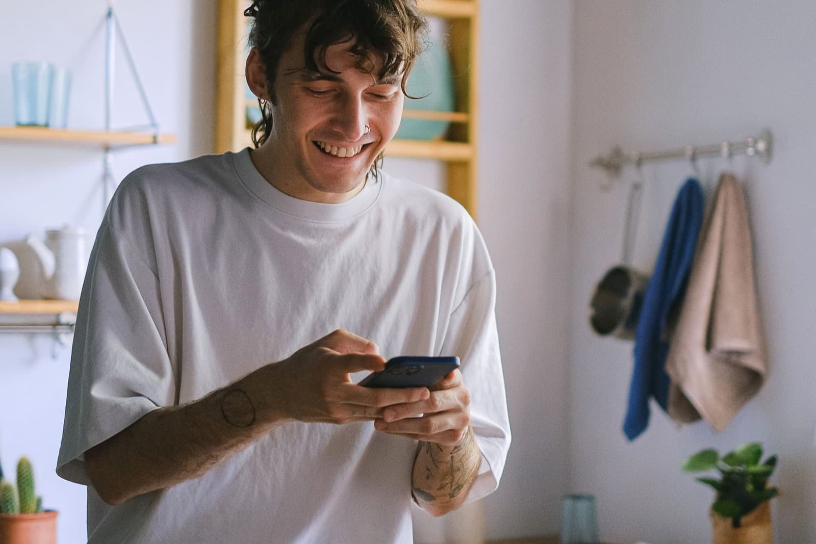 A smiling homeowner using a smartphone in a bright kitchen
