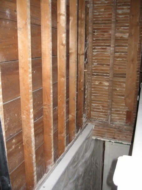 Close-up of exposed wood lath at a wall corner, showing the hardened plaster keys that grip behind it